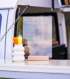 a glass sign sitting on the back of a white truck next to a candle holder