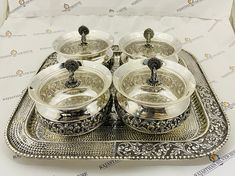 three silver pots and pans sitting on a tray