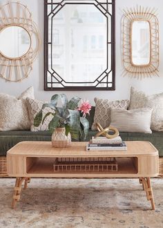 a living room with couches, tables and mirrors on the wall above them is decorated in neutral colors