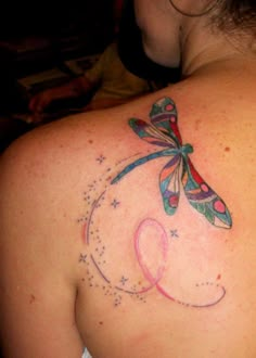 the back of a woman's shoulder with a dragonfly tattoo on her upper arm