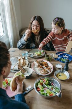 a woman and two children sitting at a table eating food