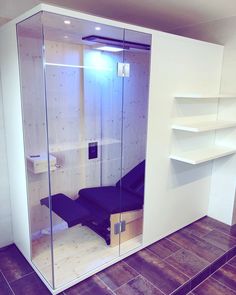 a glass walled room with a chair in the corner and shelves on the wall behind it