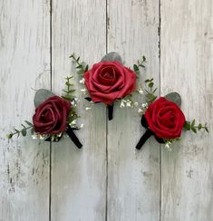 three red roses and baby's breath are placed on a white wooden surface