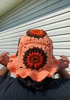 a person wearing a crocheted hat with an orange flower