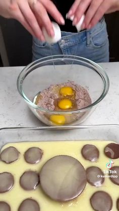 someone is mixing ingredients in a bowl on top of a table with chocolates and eggs