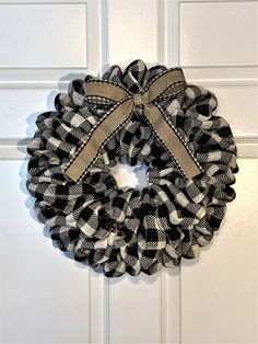 a black and white wreath hanging on the front door with burlocked ribbon