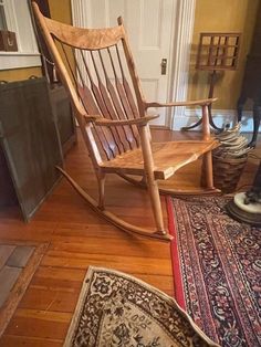 a wooden rocking chair sitting on top of a hard wood floor next to a rug