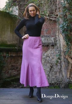 a woman in a black top and purple skirt posing for the camera with her hands on her hips