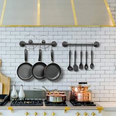 pots and pans are hanging on the wall above an oven