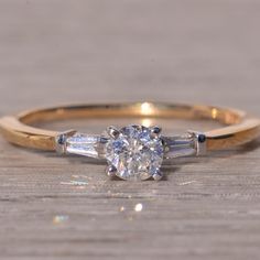 an engagement ring with three baguets on the side and a diamond in the middle