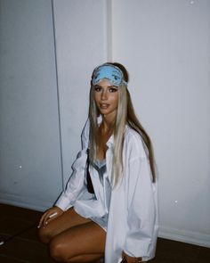 a woman sitting on the floor wearing a white shirt and blue bandana headband