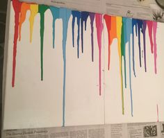 an open book with rainbow paint dripping down the pages and newspaper clippings next to it