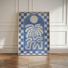 a blue and white painting sitting on top of a wooden floor next to a wall