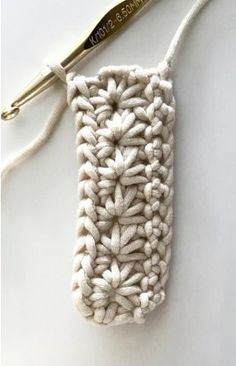 a crocheted cell phone case sitting on top of a white table next to a pair of scissors