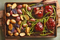 meat, potatoes and green beans in a baking dish on a cutting board with a knife