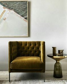 a brown chair sitting next to a table on top of a carpeted floor in front of a white wall