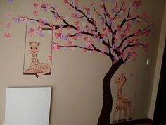 a baby's room decorated in pink and brown with giraffes on the tree