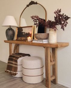 a wooden table topped with a mirror next to a vase filled with flowers and plants