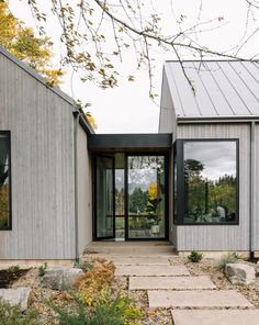 a modern house with two large windows and stone walkway leading up to the front door