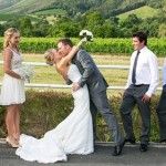 a bride and groom kissing in front of their wedding party on the side of the road