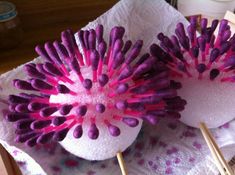 two pink and purple flowers on sticks in a box with paper napkins next to it