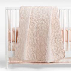 a white crib with a pink blanket on it