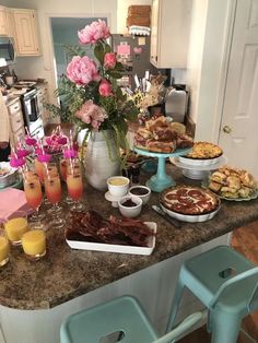 a kitchen counter topped with plates and bowls filled with food next to cups full of juice