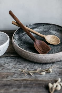 two wooden spoons and a bowl on a table