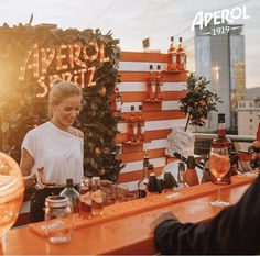 a woman standing behind a bar filled with bottles and glasses