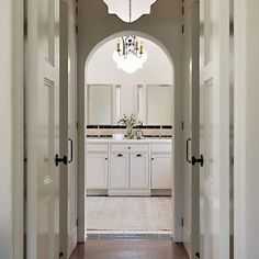 an archway leads into a large bathroom with double sinks and mirrors on either side of the door