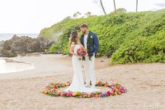 a bride and groom standing on the beach in front of their wedding ceremony wreaths