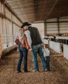 a man and woman are holding their son's hand as they stand in the hay