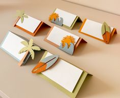 some cards are sitting on a table with paper flowers and palm trees in the middle