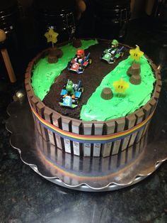 a cake with green frosting on top of a metal platter that has cars and trees in it