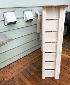 a white cabinet sitting on top of a wooden floor next to a wall mounted toilet paper dispenser