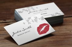 two business cards with red lips on them sitting on a wooden table next to each other