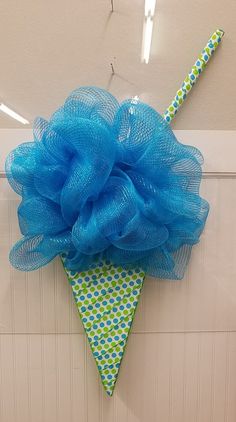 an ice cream cone decorated with blue mesh and a green polka dot bow hanging on the wall