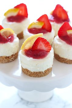 mini cheesecakes with strawberries and lemon slices on a white plate, ready to be eaten