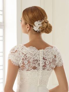 the back of a woman's wedding dress with an intricate hair comb in her hair