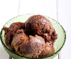 three scoops of ice cream in a green bowl on a white wooden table top