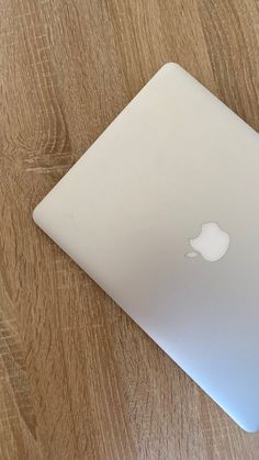 an apple laptop sitting on top of a wooden table