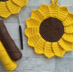 two crocheted sunflowers sitting on top of a table next to yarn