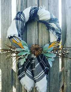 a wreath is hanging on the side of a wooden fence with leaves and grass around it