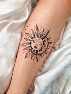 a woman's arm with a sun and moon tattoo on the left side of her leg