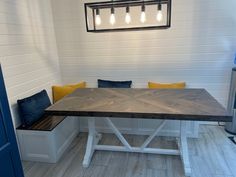 a dining room table with benches and lights hanging from it's ceiling over the bench