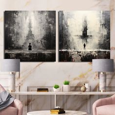 two black and white paintings on the wall above a coffee table with pink chairs in front of it