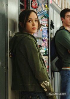 two young people standing in front of a locker with stickers on it and looking at the camera