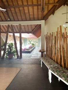 the inside of a house with wood beams and plants on the wall, along with a bench