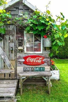 an old wooden shack with a coca cola sign on the door and bench next to it