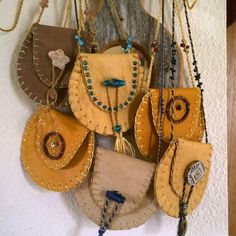 an assortment of purses hanging on a wall with chains and beaded necklaces